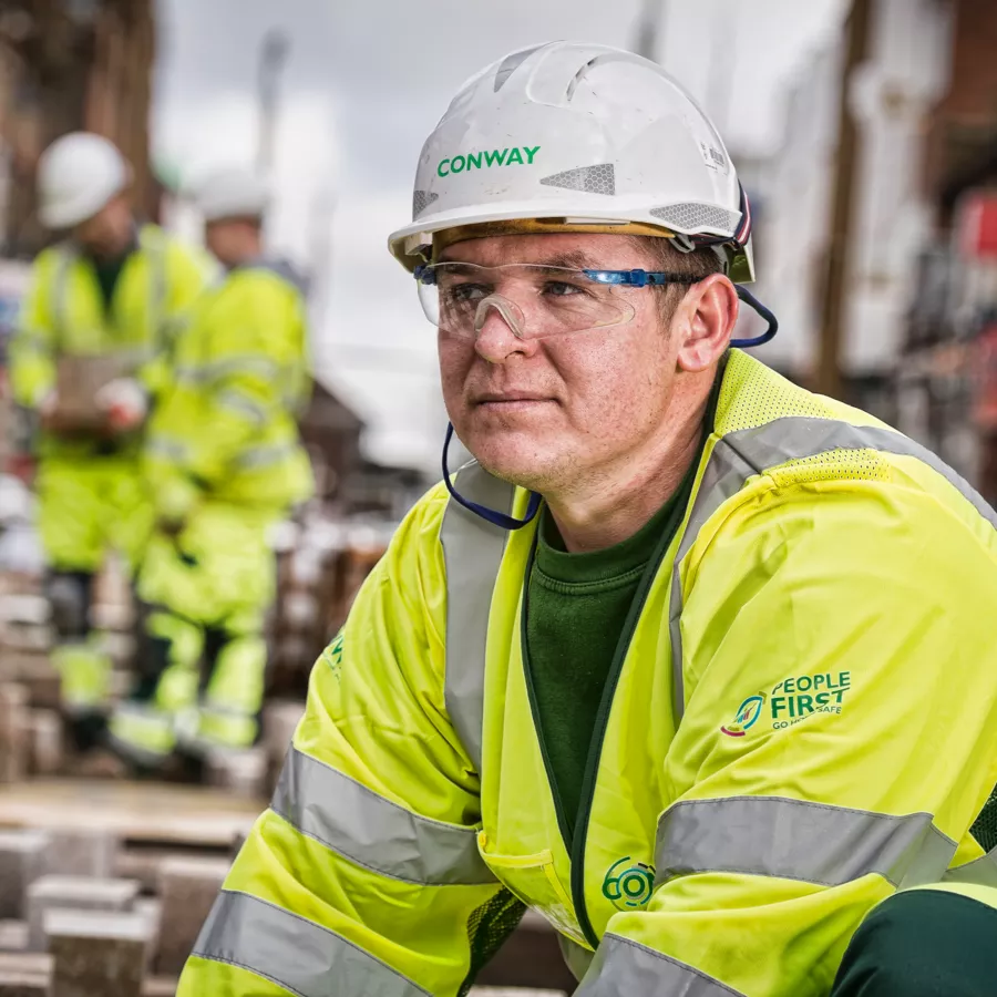 A person in FM Conway branded high viz, safety glasses and hard hat 