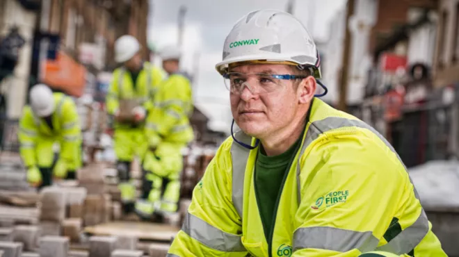 A person in FM Conway branded high viz, safety glasses and hard hat 